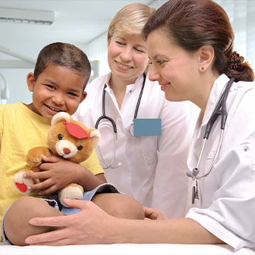 A little boy smiles and squeezes a teddy bear to his chest during his checkup. Links to Closely Held Business Stock